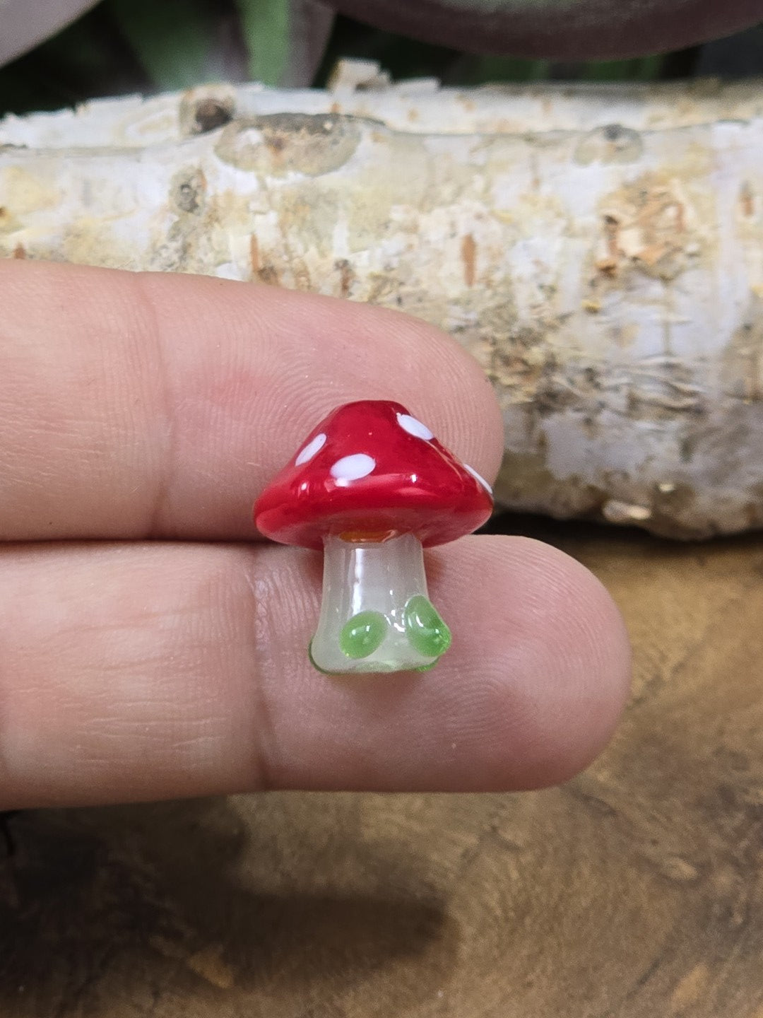 Kleine Pilzperle aus Glas mit rotem Hut, weißen Punkten und hellem Stiel zur Größendarstellung