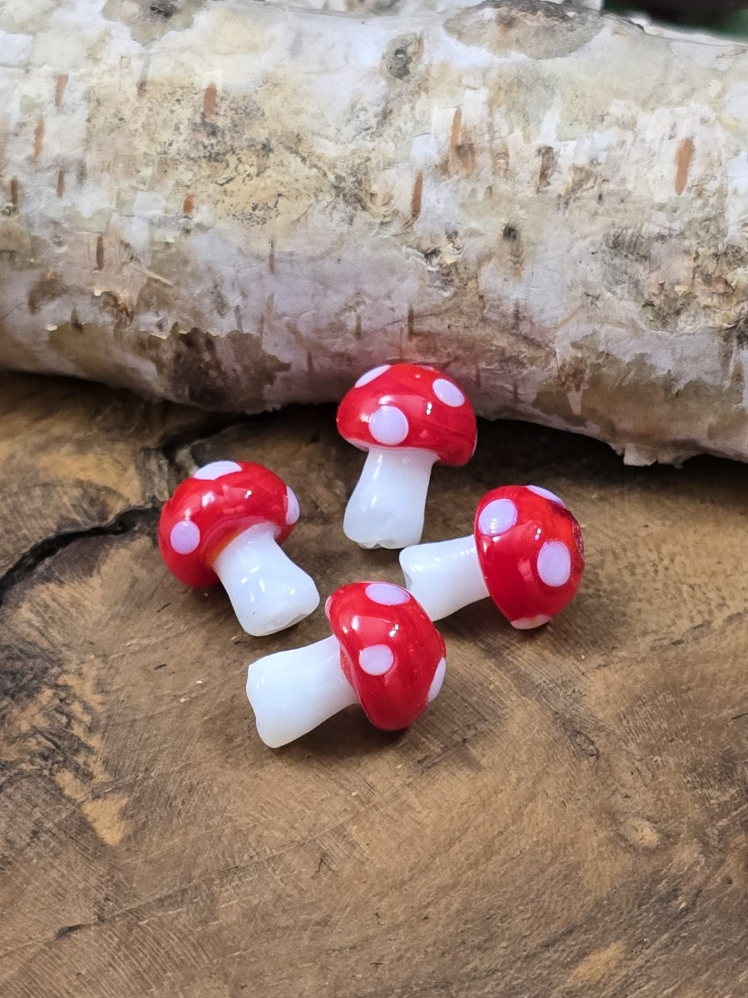 Vier kleine Fliegenpilz-Glasperlen mit roten Hüten und weißen Punkten für DIY-Schmuck
