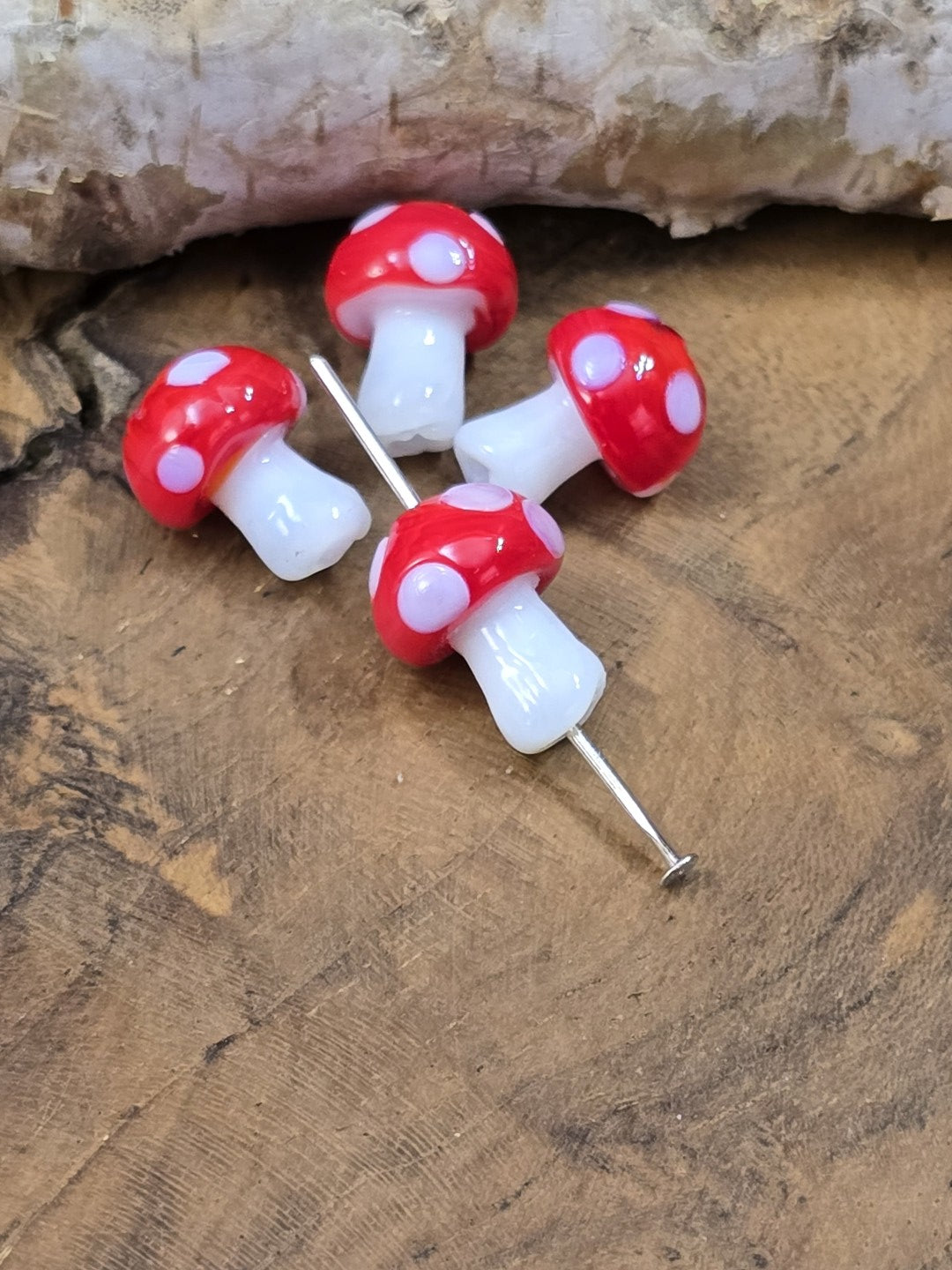 Detailaufnahme roter Pilz-Glasperlen mit weißen Punkten und sichtbarer Lochbohrung