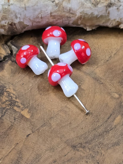 Detailaufnahme roter Pilz-Glasperlen mit weißen Punkten und sichtbarer Lochbohrung