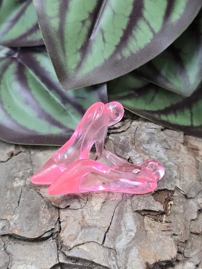 Zwei rosa transparente High-Heel-Anhänger aus Acryl auf rustikalem Hintergrund