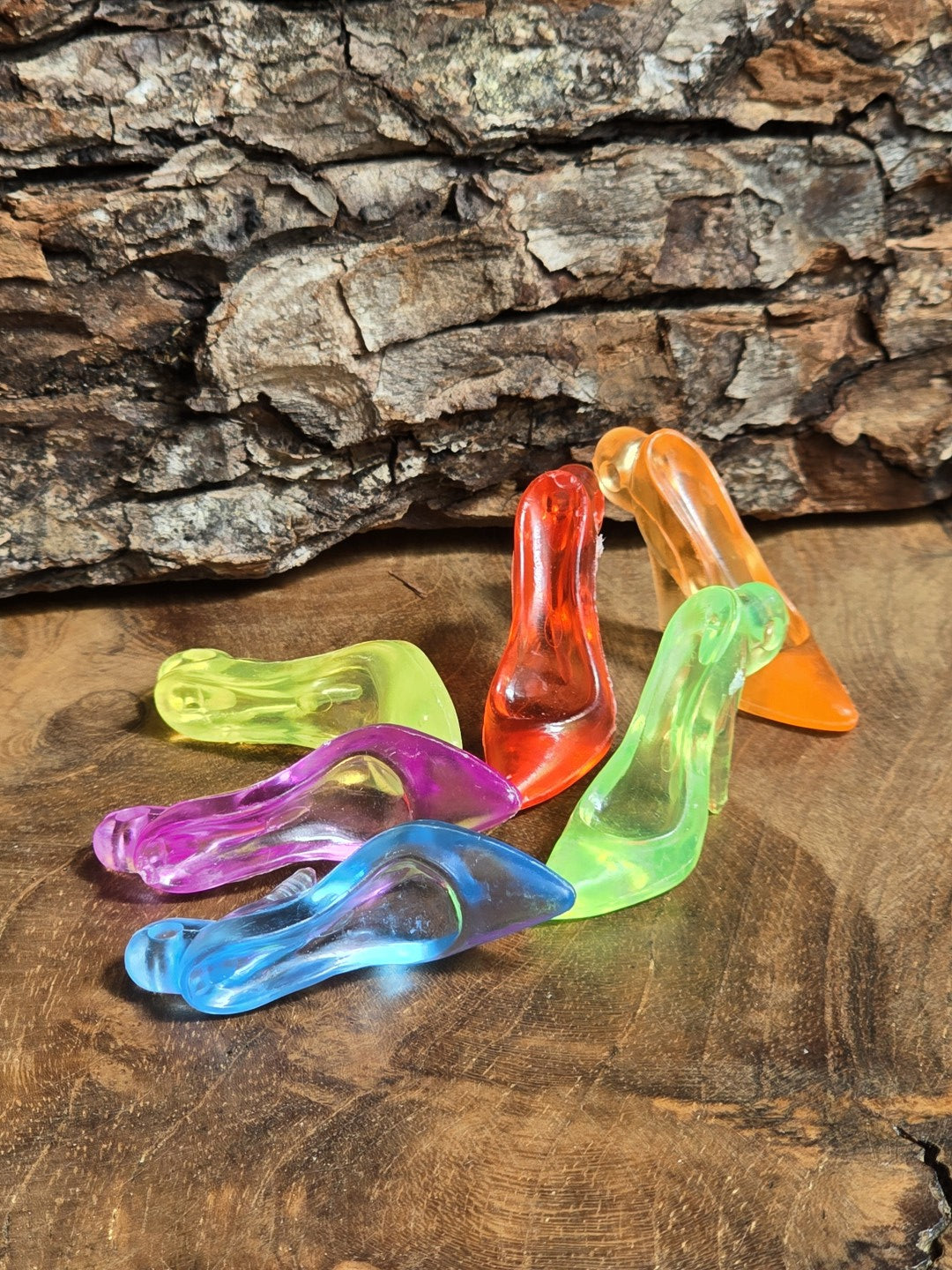 Bunter Mix aus transparenten Pumps-Anhängern aus Acryl in verschiedenen Farben auf Holzgrund