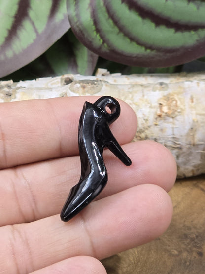 Detailaufnahme eines schwarzen Pumps-Anhängers aus Acryl in der Hand zur Größendarstellung
