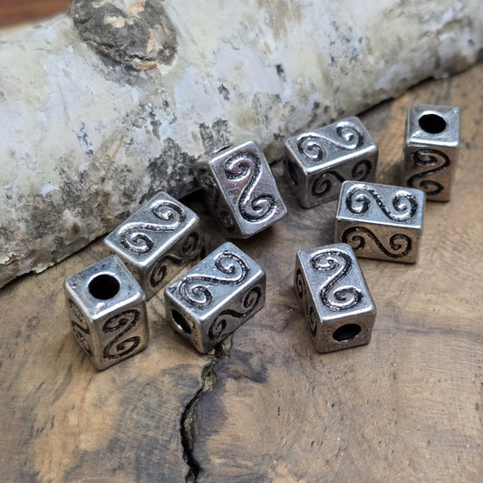 Eckige Metallperlen in Antiksilber mit S-förmigem Gravurmuster. Die strukturierte Oberfläche sorgt für einen eleganten Akzent. Mit einer Größe von 11 mm eignen sie sich perfekt für Armbänder, Ketten und kreative Schmuckdesigns.