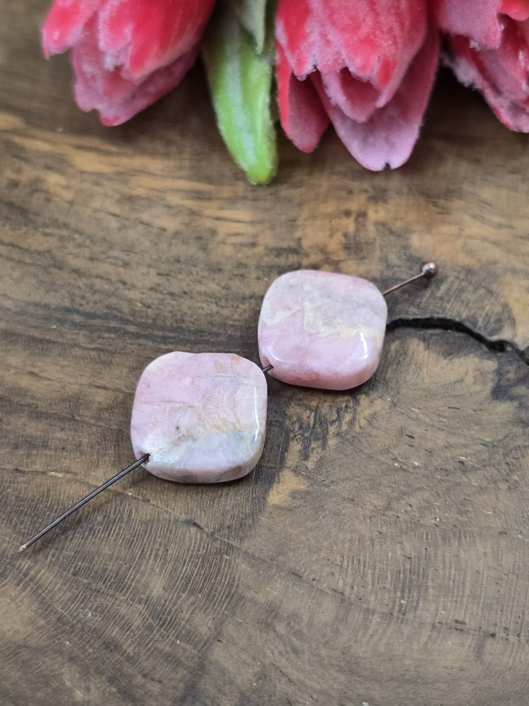 Draufsicht auf zwei rosa Rhodochrosit-Perlen (13,6 mm) auf Nietstift zur Darstellung von Maserung und Fädelbohrung.