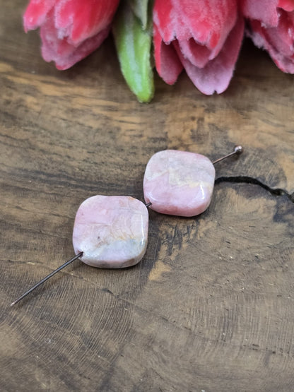 Draufsicht auf zwei rosa Rhodochrosit-Perlen (13,6 mm) auf Nietstift zur Darstellung von Maserung und Fädelbohrung.