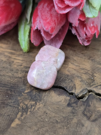 Zwei rosa-marmorierte Rhodochrosit-Natursteinperlen (13,6 mm) übereinander auf rustikalem Holzgrund.