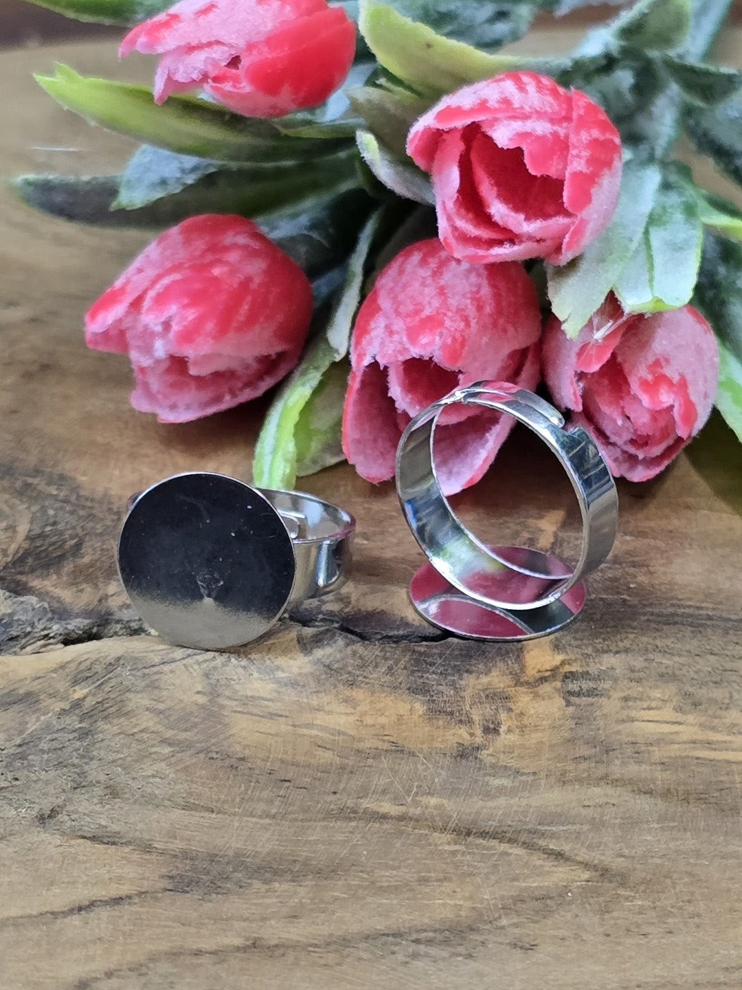 Verstellbare Ringschienen in Rhodium-Optik mit runder 15mm Klebefläche für DIY-Schmuck vor Blütendekoration.