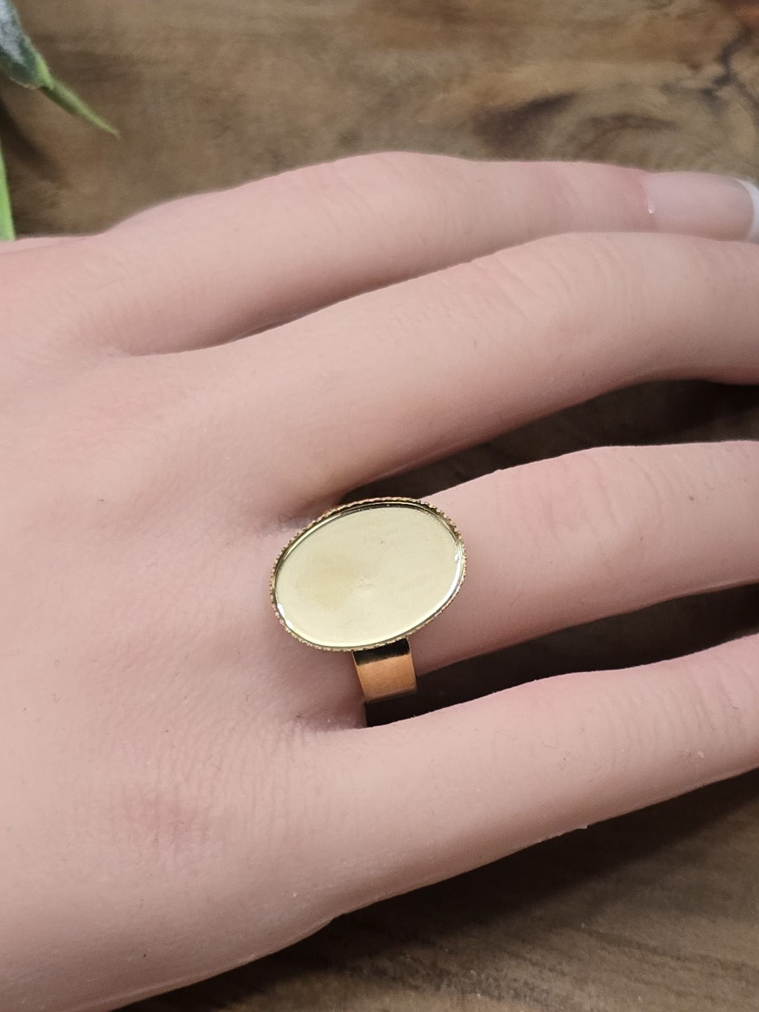 Goldener verstellbarer Ringrohling mit ovaler Klebefläche an der Hand als Größenvergleich für DIY-Schmuckprojekte.