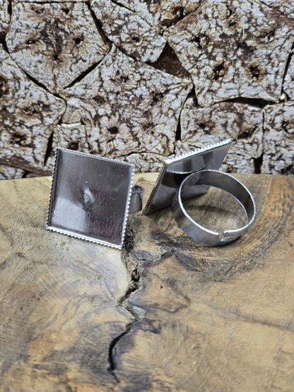 Zwei verstellbare Ringschienen in Silber mit quadratischer Klebefläche (19 mm) auf natürlichem Holzuntergrund.