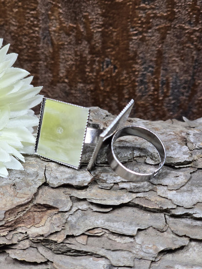 Silberne Ringrohlinge mit quadratischer Platte für Cabochons, stilvoll inszeniert mit weißer Blüte auf Baumrinde.