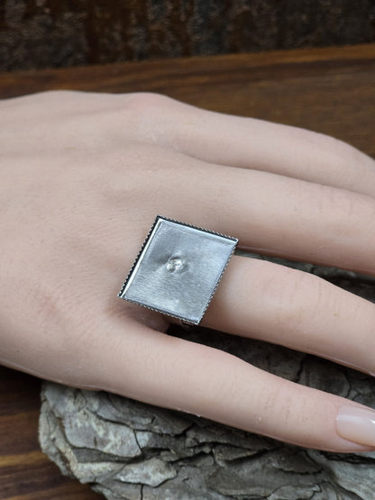 Silberner verstellbarer Ring mit quadratischer 19-mm-Platte an einer Hand zur Veranschaulichung der Größe und Passform.