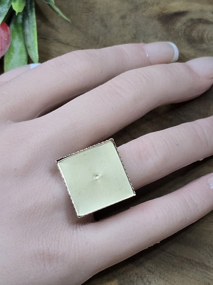 Goldfarbene verstellbare Ringschiene mit quadratischer 19-mm-Platte an der Hand als Größenvergleich für Cabochon-Projekte.