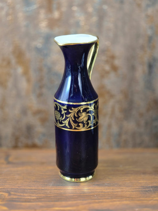 Vintage Porzellanvase in tiefem Kobaltblau mit breitem Golddekor, schmaler Krugform und goldfarbenem Henkel in leichter Seitenansicht.