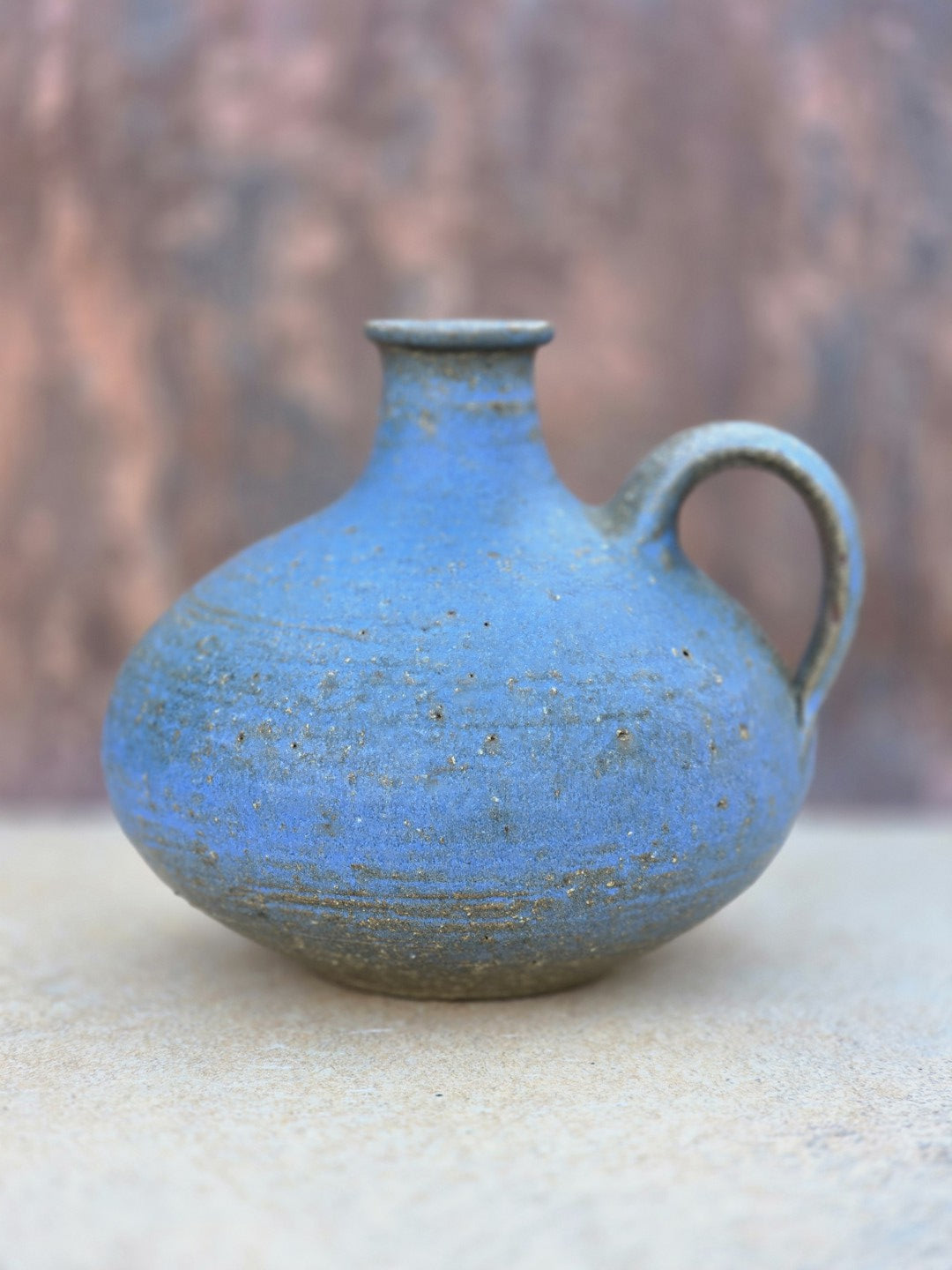 Kleine bauchige Studiokeramikvase von Rudi Stahl mit kräftiger blauer Farbe, matter Oberfläche, Henkel und geritzter Signatur am rotbraunen Boden.