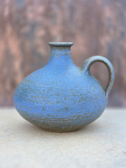 Kleine bauchige Studiokeramikvase von Rudi Stahl mit kräftiger blauer Farbe, matter Oberfläche, Henkel und geritzter Signatur am rotbraunen Boden.
