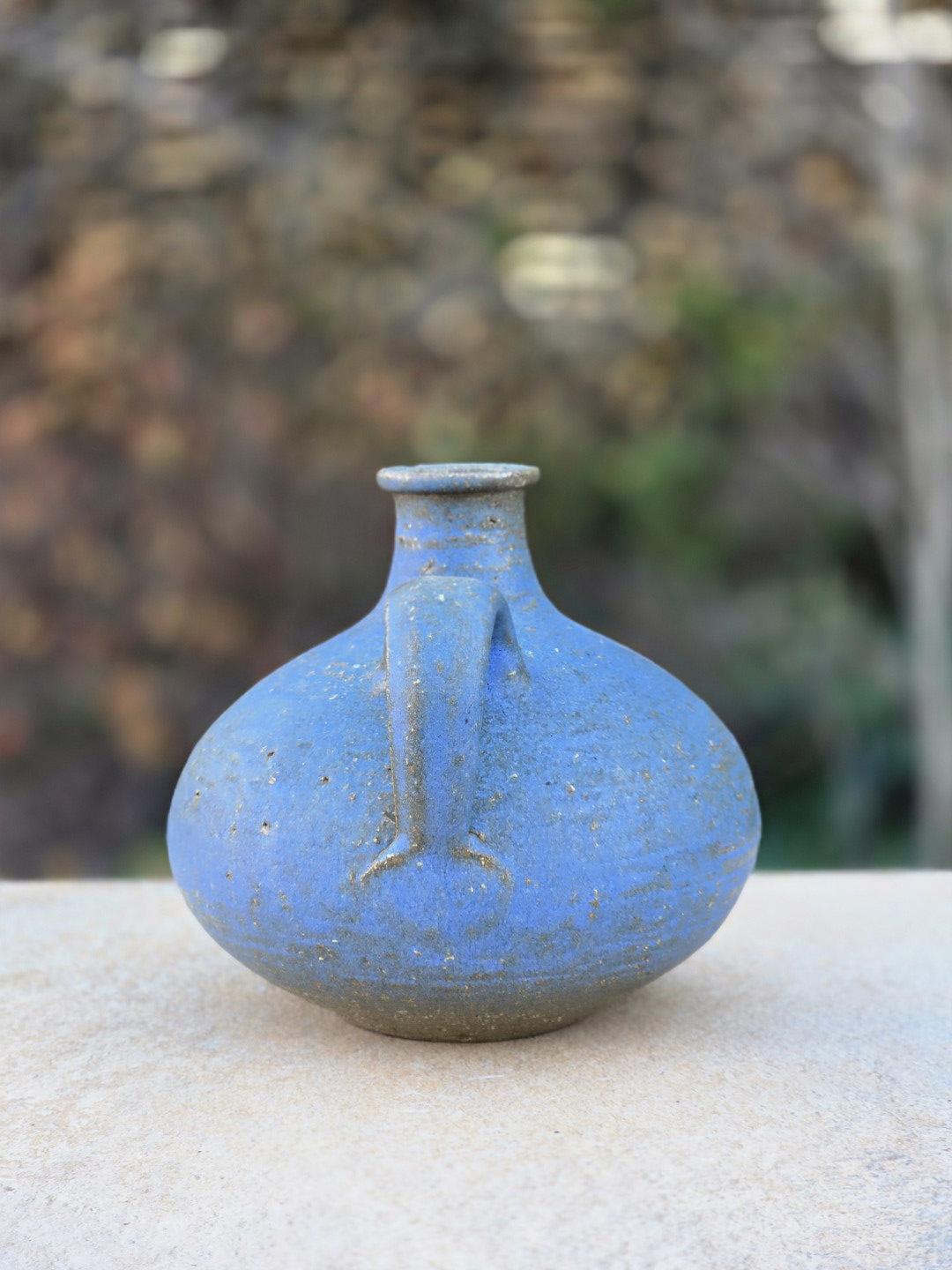 Rudi Stahl Studiokeramik in Blau mit bauchiger Vasenform, kleinem Henkel, matter körniger Oberfläche und sichtbarem rotbraunem Scherben.