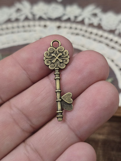 Schlüssel-Anhänger 34x11mm in Bronze-Optik quer auf Fingern gehalten als Größenvergleich.