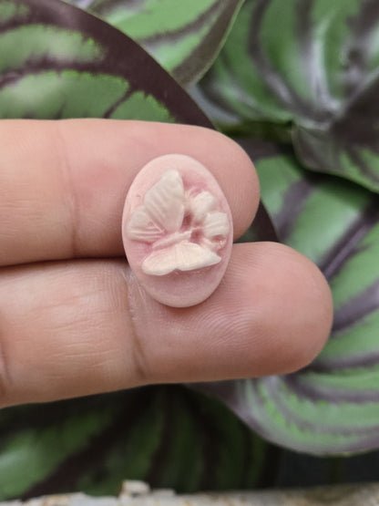 Kleiner altrosa Schmetterling Cabochon auf Fingerspitzen zur Größendarstellung