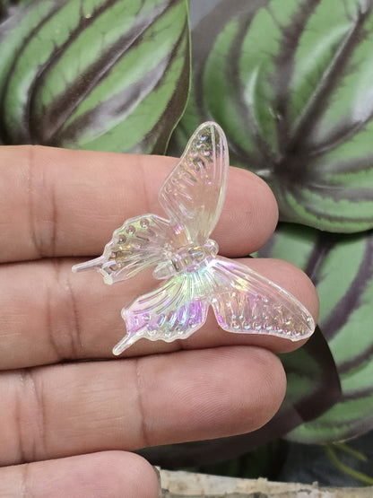 Farbloser Acryl-Schmetterling mit Regenbogenglanz auf den Fingern als Größenvergleich