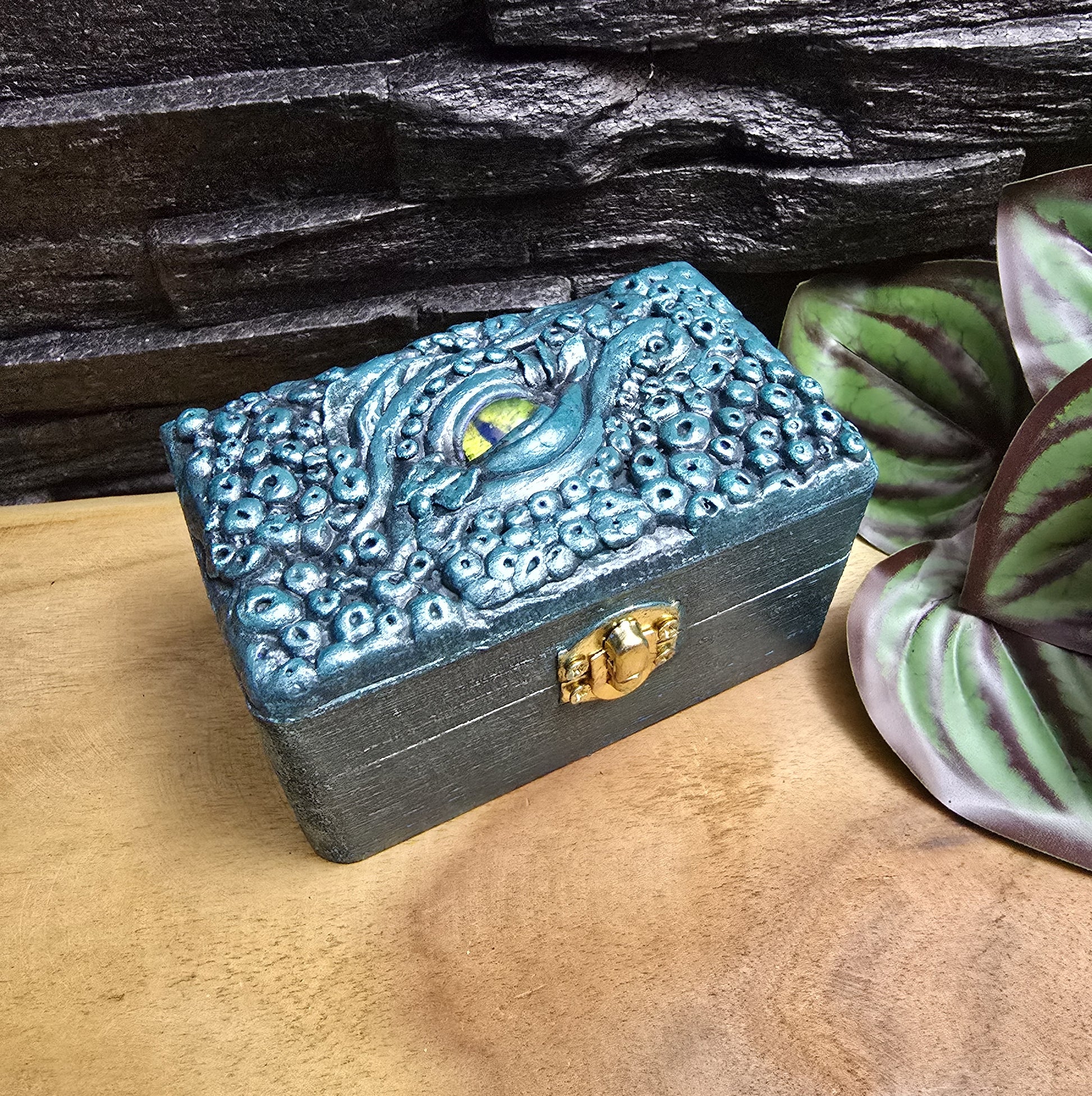 Das Bild zeigt eine geheimnisvolle Schatulle Auge des Oktopus, Meeresgrün, mit Samtkissen und Schnappverschluss. Ladetruhe, Würfelbox, Schmuckkiste

Ob als Schmuckschatulle, Ladebox, Würfelbox oder für andere Kostbarkeiten – diese einzigartige Truhe ist nicht nur ein praktisches Behältnis, sondern ein magisches Artefakt, das die Geschichten der Meere in sich trägt.