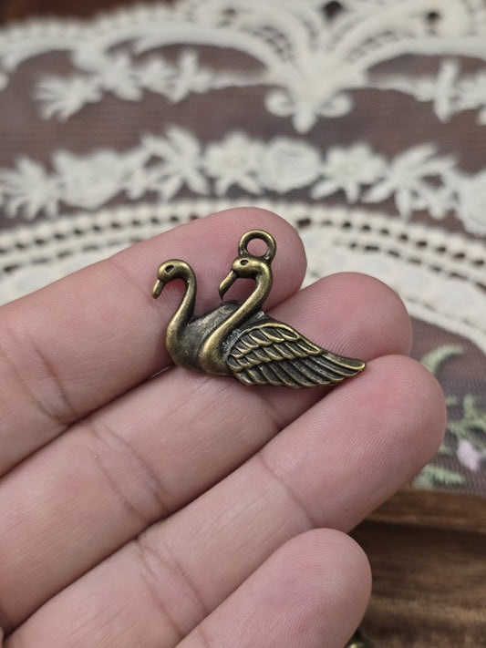 Schwanen-Schmuckanhänger 21x28mm in Bronze-Optik gehalten in der Hand als Größenvergleich.
