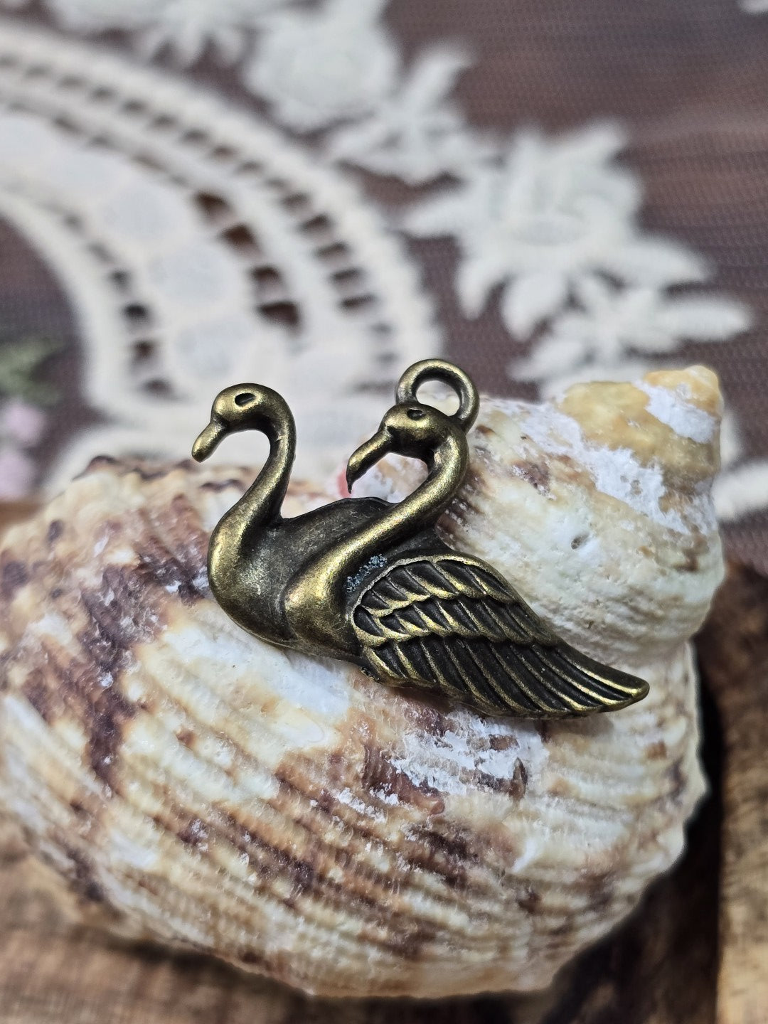 Schwan-Anhänger in Antik-Bronze mit Öse dekoriert auf einer Muschel.