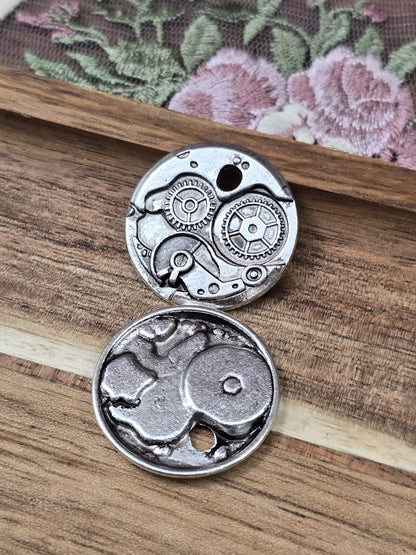 Vorderseite und Rückseite des runden Steampunk Metallanhängers mit Zahnrädern auf Holz.