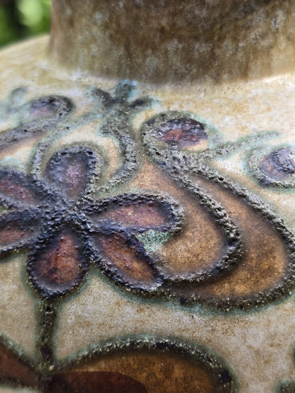 Nahaufnahme des floralen Reliefdekors mit braunen Blättern, grünen Konturen und rauer Struktur
