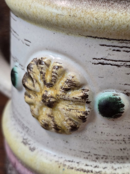 Vintage Keramikbecher mit plastischem gelb-braunem Blütenrelief und grün glasiertem Punktdekor in detaillierter Nahaufnahme