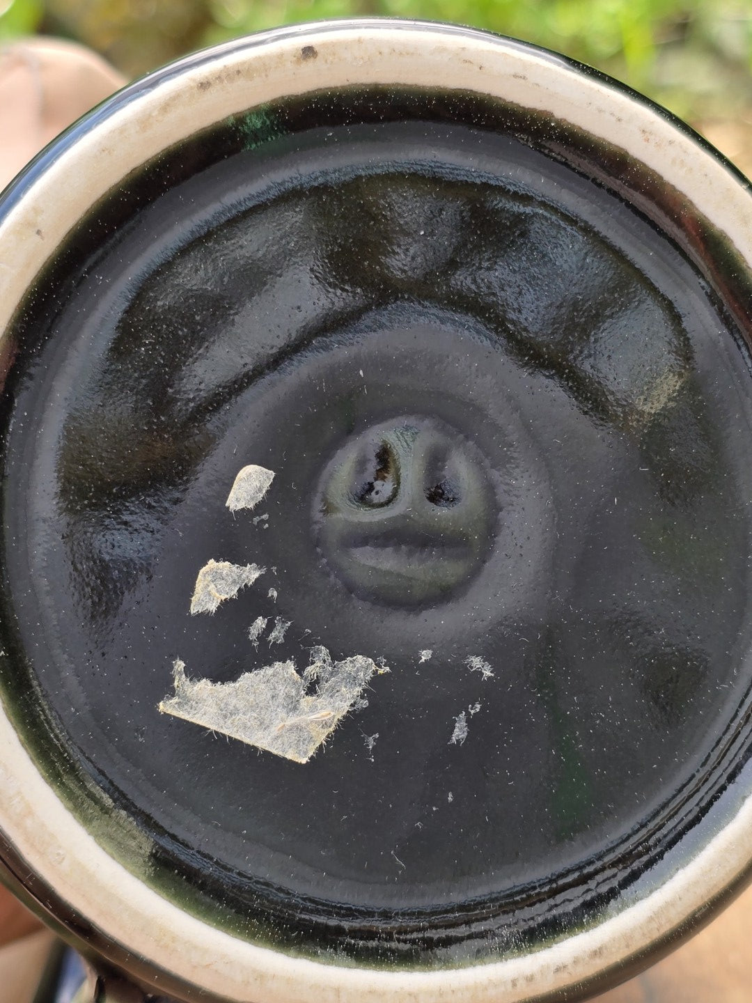 Unterseite eines Vintage Steingut Bierseidels mit dunkler Glasur und alten Aufkleberresten
