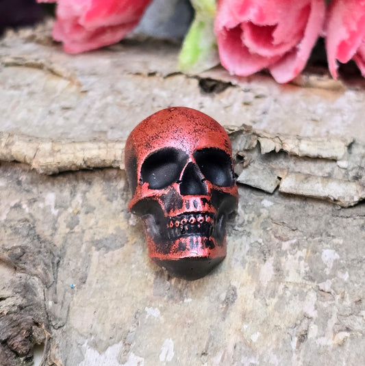 Das Bild zeigt einen Totenkopf-Cabochon in Schwarz mit roter Wachsverzierung