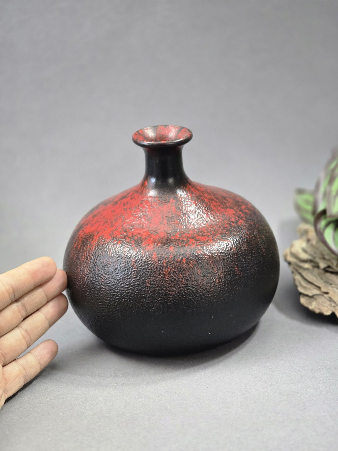Runde schwarz rote Vase mit Größenvergleich durch Hand, strukturierter Glasur und kompakter dekorativer Form