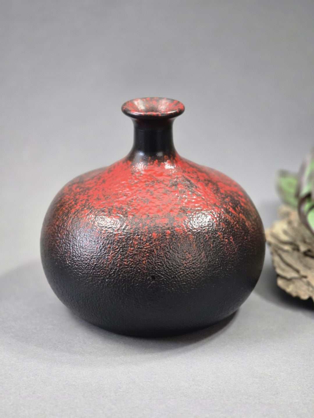 Dekorative Vase in Schwarz Rot mit glänzender Struktur, schmaler Öffnung und ruhiger Studioaufnahme