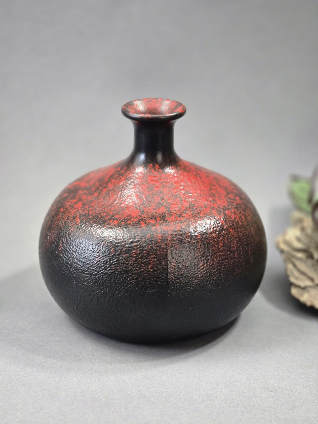 Detailbild der strukturierten Oberfläche einer rot schwarzen Vintage Vase mit kleinen sichtbaren Gebrauchsspuren