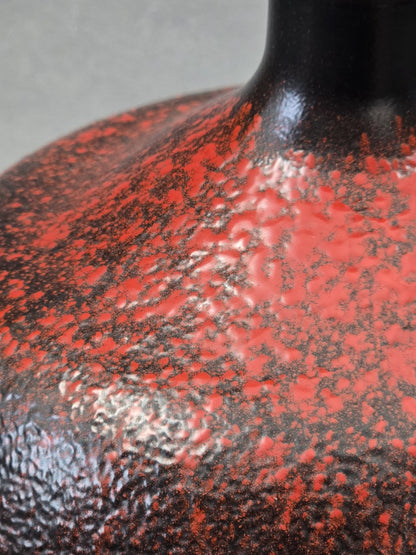 Makroaufnahme der lebendigen rot schwarzen Glasurstruktur auf einer bauchigen Vintage Vase