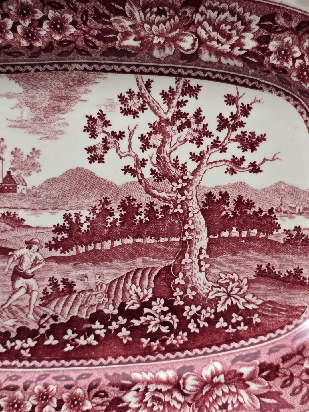 Vintage Rusticana Servierplatte mit rotem Landschaftsdekor, großem Baum, Figuren und floralem Rand in vergrößerter Detailaufnahme