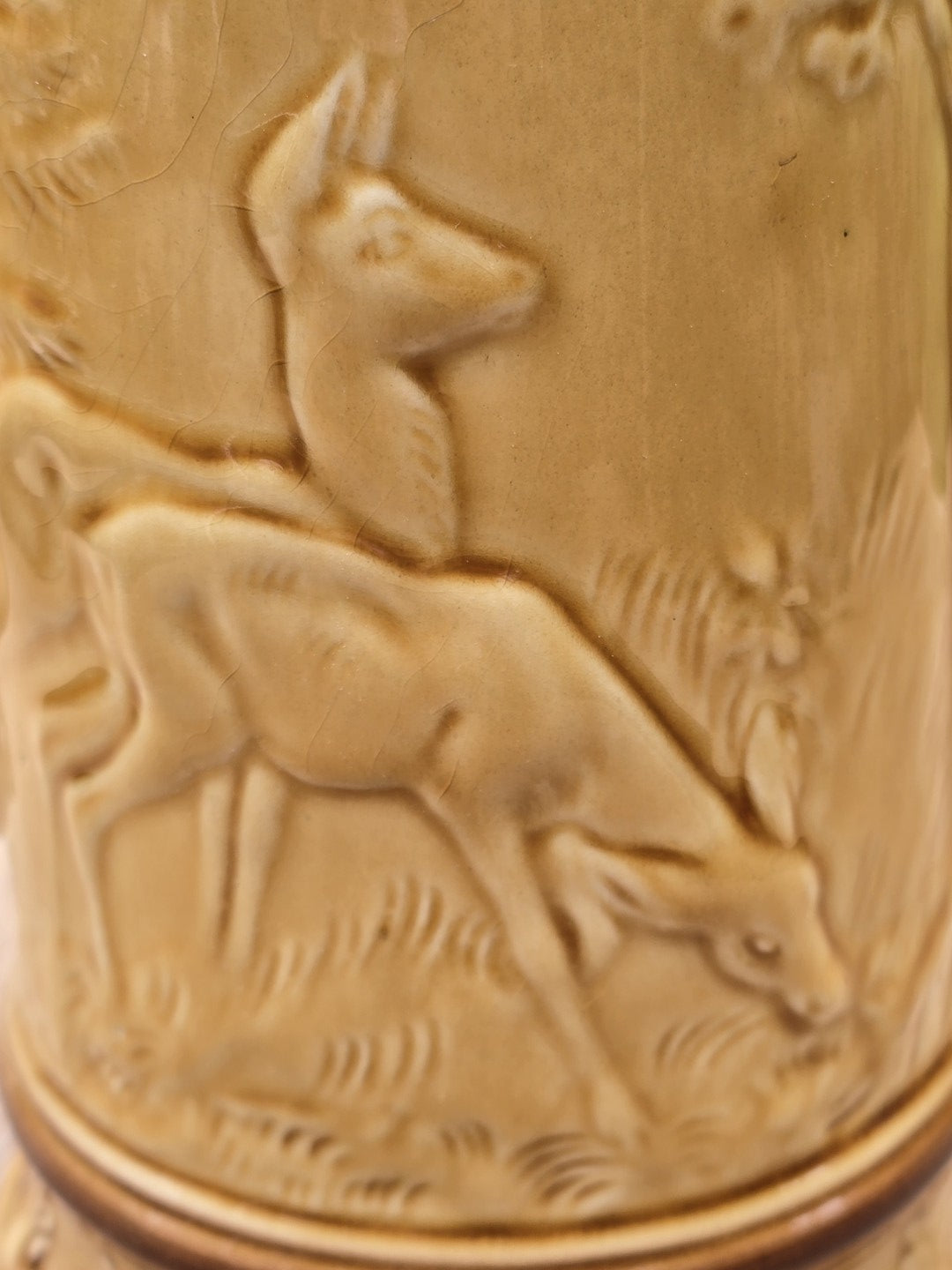 Makroaufnahme vom Hirschrelief auf honiggelbem Keramik Bierkrug mit sichtbarer Glasurstruktur und feinem Craquelé