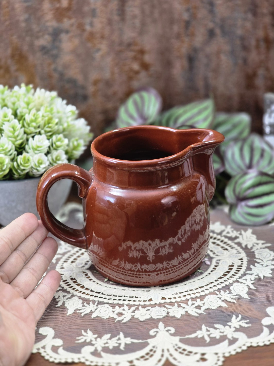 Vintage DDR Milchkännchen aus braunem Steingut mit geschwungenem Henkel und heller Ornamentbordüre mit Hand als Größenvergleich