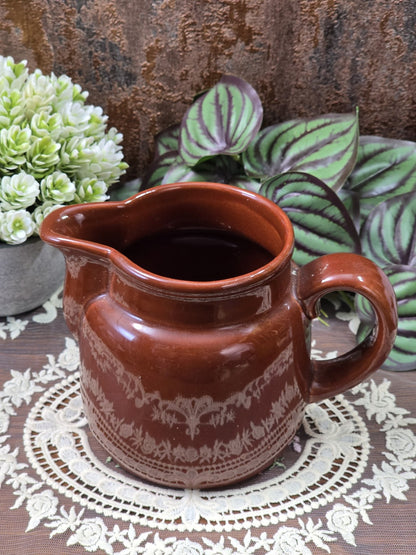 Vintage DDR Milchkännchen aus braun glasierter Keramik mit Henkel und floral wirkender Bordüre, leicht erhöht von vorn fotografiert
