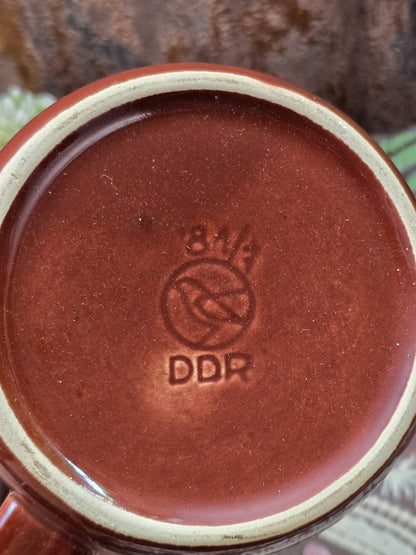 Vintage Steingut Milchkännchen mit brauner Unterseite, hellem Standring und sichtbarer Bodenmarke mit DDR-Schriftzug in Nahaufnahme