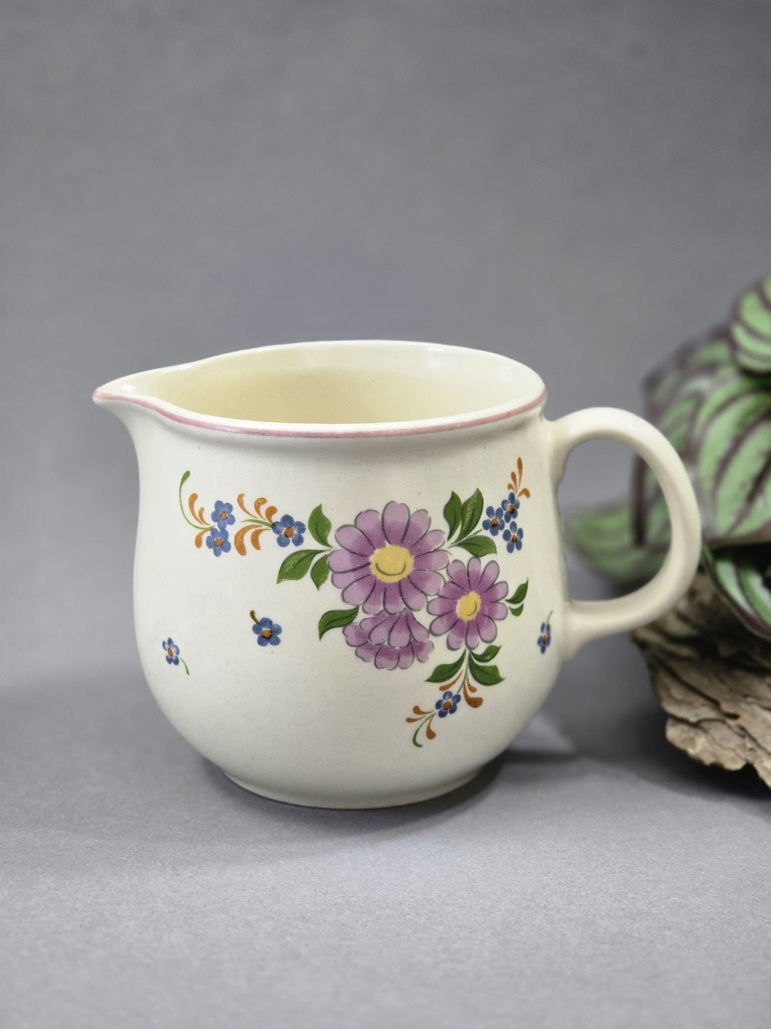 Cremefarbenes Vintage-Milchkännchen aus Keramik mit rosa Blumen, kleinen blauen Blüten, grünem Blattdekor und seitlichem Henkel