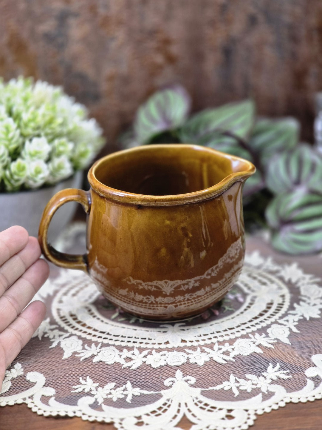 Vintage DDR Milchkännchen in Honigbraun mit bauchiger Form, geschwungenem Ausguss und hellem Bordürendekor mit Hand als Größenvergleich