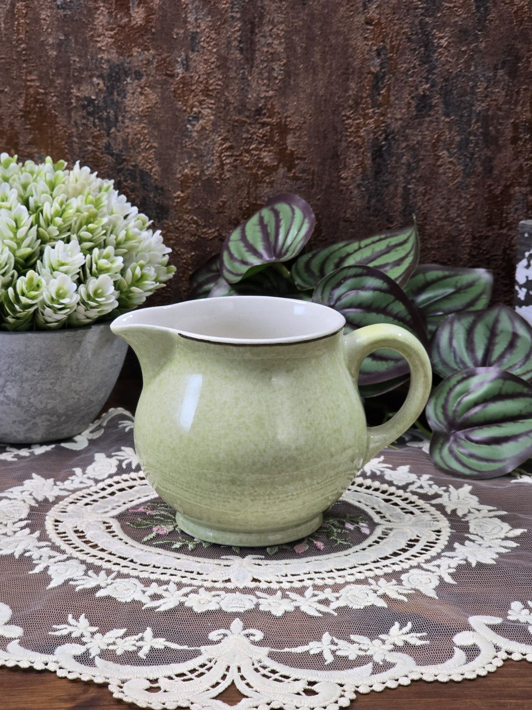 Vintage Dresden Milchkännchen aus pastellgrün glasierter Keramik mit bauchiger Form, Henkel, Ausguss und dunklem Rand in Frontalansicht