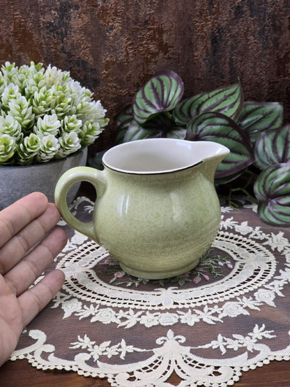 Vintage Dresden Milchkännchen in Pastellgrün mit rundem Korpus, geschwungenem Henkel und dunkler Randlinie mit Hand als Größenvergleich