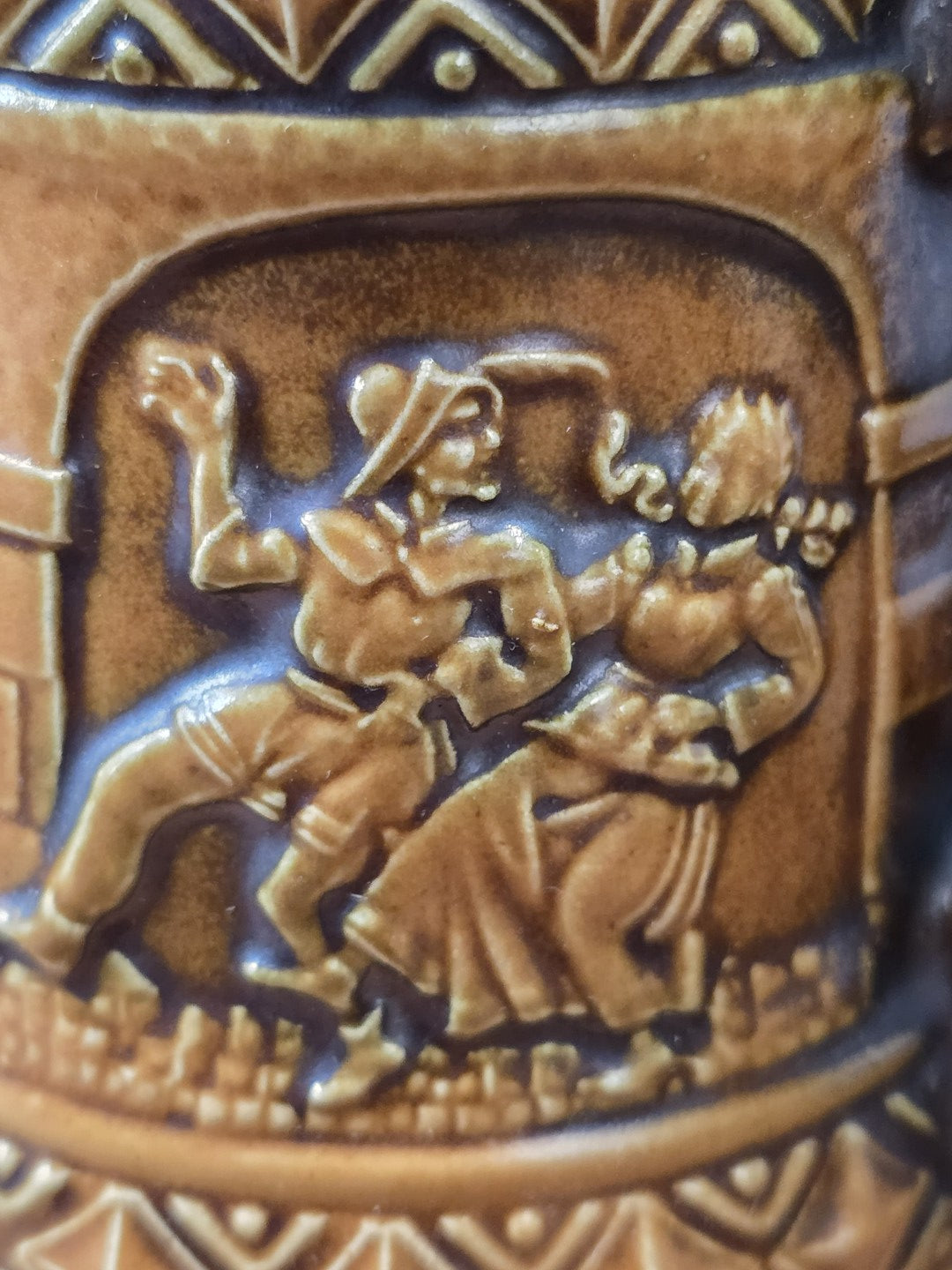 Vintage Gerzit Bierkrug mit brauner Reliefglasur und plastischem Tanzpaar in historisierender Kleidung in Nahaufnahme.