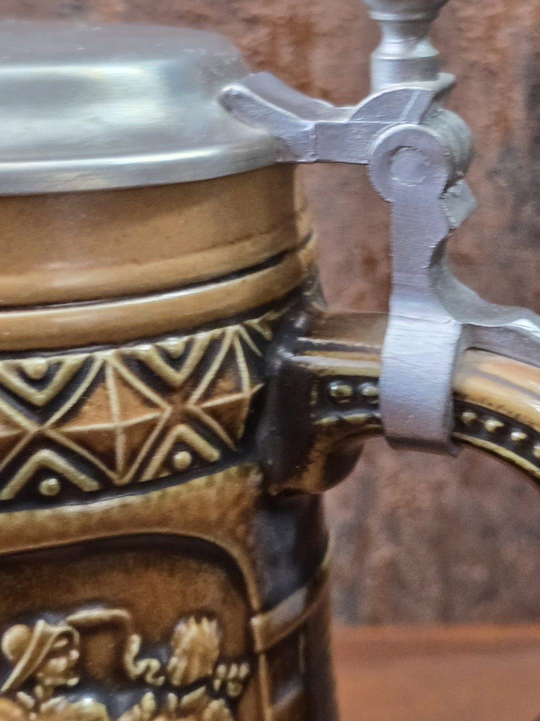 Vintage Gerzit Bierkrug mit Zinndeckel und Scharniermechanik in Nahaufnahme, daneben braune Glasur und geometrisches Reliefband.