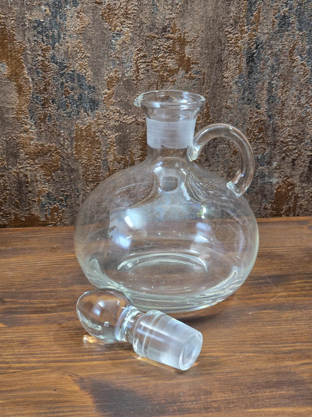 Vintage Glasdekanter mit abgenommenem Glasstöpsel, rundem Korpus und weitem Hals auf Holztisch