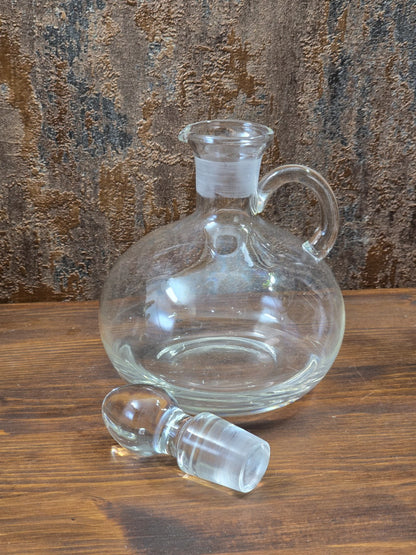 Vintage Glasdekanter mit abgenommenem Glasstöpsel, rundem Korpus und weitem Hals auf Holztisch
