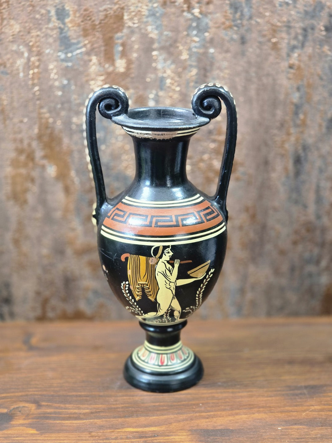 Vintage Keramikamphora mit antikisierendem Figurenmotiv, terracottafarbenem Mäanderdekor und geschwungenen Henkeln auf Holztisch